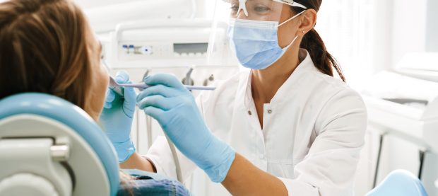 European mid dentist woman in face mask working in dental clinic European mid pleased dentist woman in face mask working in dental clinic