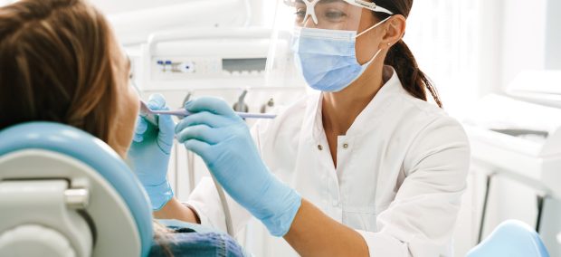 European mid dentist woman in face mask working in dental clinic European mid pleased dentist woman in face mask working in dental clinic
